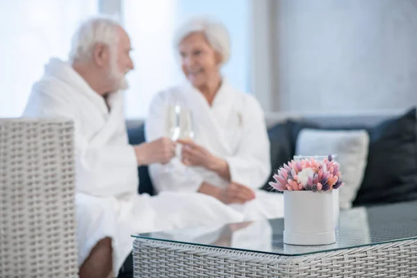 Старшая пара в белых халатах празднует и выглядит счастливой — стоковое фото
