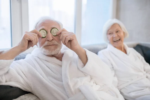 Pareja mayor con túnicas blancas disfrutando de los procedimientos de spa y divirtiéndose — Foto de Stock