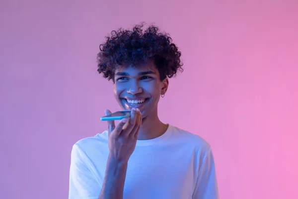 Curly-haired smiling guy recording a voice message and smiling — Stock Photo, Image