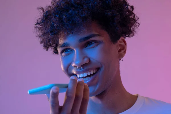 Curly-haired smiling guy recording a voice message and smiling — Stock Photo, Image