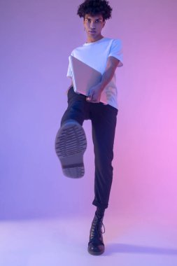 Beyaz tişörtlü, dizüstü bilgisayarlı Afro-Amerikan genç adam...