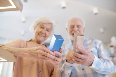 Gri saçlı çift parfüm seçiyor ve heyecanlı görünüyorlar.