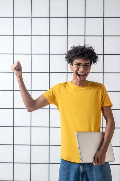 Africano americano jovem cara em óculos segurando um laptop e se sentindo incrível — Fotografia de Stock