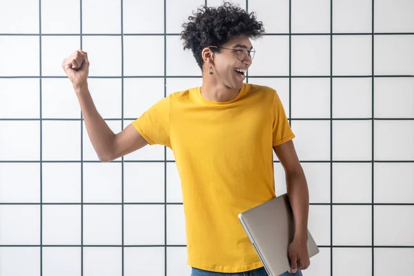 Afroamericano giovane ragazzo in occhiali in possesso di un computer portatile e sentirsi impressionante — Foto Stock