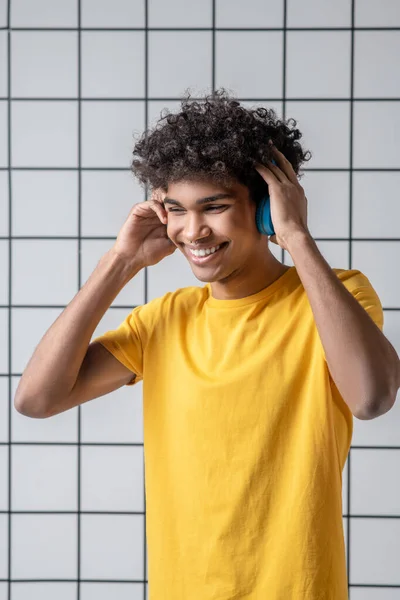 Afro americano joven chico en auriculares sonriendo y buscando satisfecho — Foto de Stock