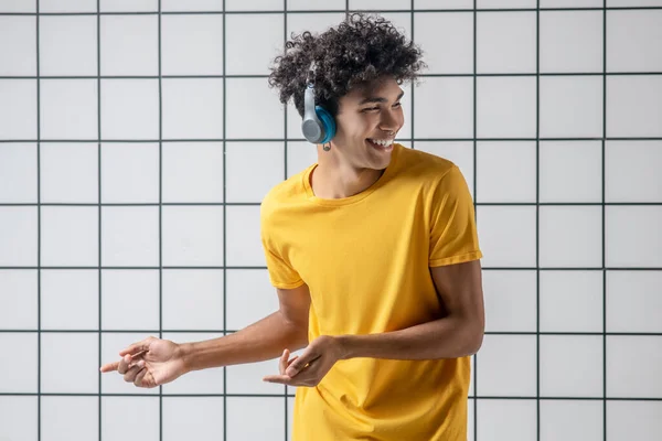 African american young guy in earphones listening to music and dancing