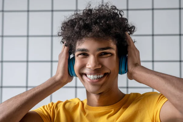 Afro americano joven chico en auriculares sonriendo y mirando feliz —  Fotos de Stock