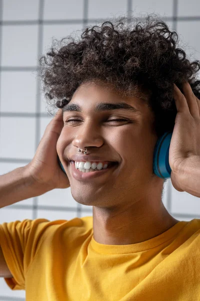 Afro americano joven chico en auriculares sonriendo y mirando feliz —  Fotos de Stock