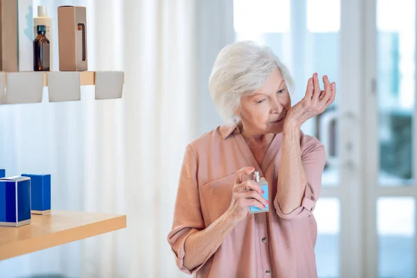 Mujer de pelo gris probando perfumes en un salón de belleza — Foto de Stock