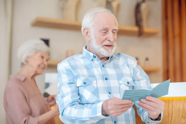 Hombre barbudo de pelo gris leyendo algo y buscando involucrado — Foto de Stock