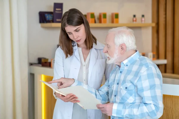 Cosmetólogo con una bata blanca hablando con un cliente masculino — Foto de Stock