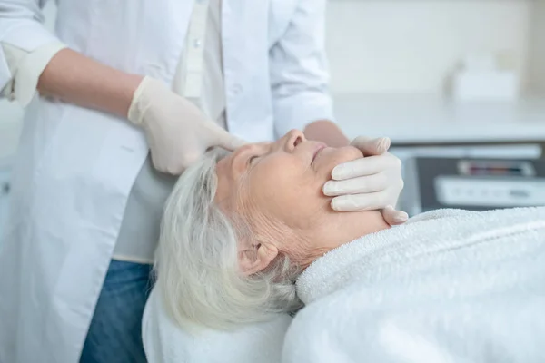 Volwassen vrouw genieten gezicht massage en op zoek ontspannen — Stockfoto