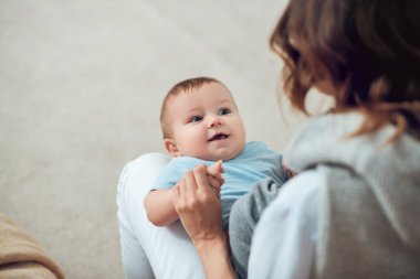 Smiling baby lying on moms lap