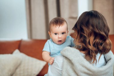 Little cute baby in moms arms at home
