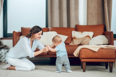 Mother sitting on floor holding baby hands