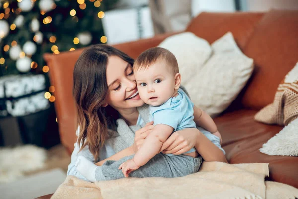 Happy mother with drooping eyelids touching baby — 图库照片