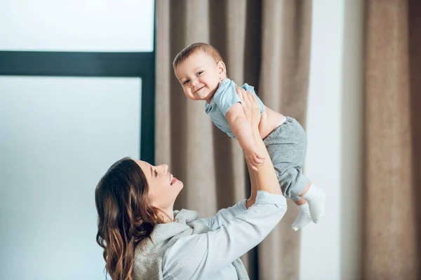 Happy mom raising up happy little child — Stockfoto