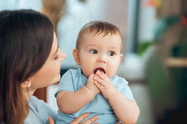 Kid holding hands near open mouth and mom — Stockfoto