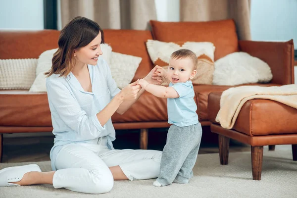 Mom sitting on floor and standing baby — Fotografia de Stock