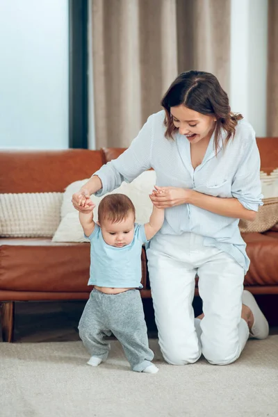 Enthusiastic woman kneeling near child taking step — Fotografia de Stock