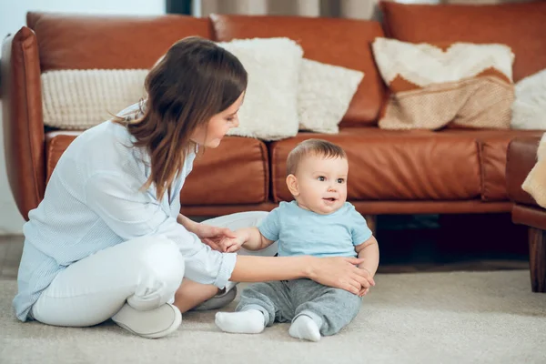 Attentive mother supporting child sitting on floor — Foto de Stock