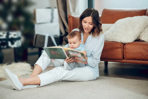 Woman sitting on floor with child reading book — Fotografia de Stock