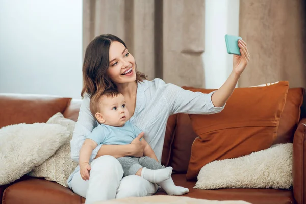 Woman taking selfie with child on couch — Stock Fotó