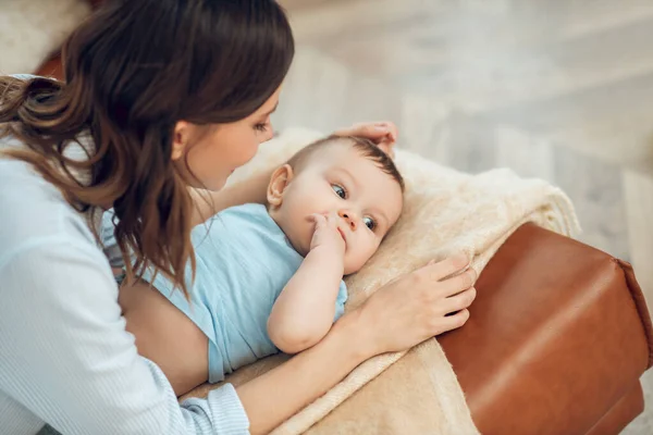 Woman looking down at child lying on sofa — 图库照片