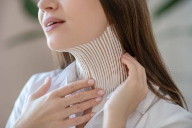 Young woman putting tapes on her neck muscle and smiling