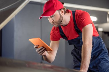 Man interested looking at tablet under hood