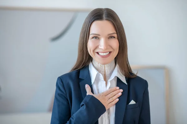 Picture of a young woman putting hand on her heart and smiling — Fotografia de Stock