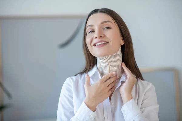 Cute young woman putting tapes on her neck muscle and smiling — Stockfoto