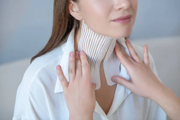 Primer plano de una joven que visita el centro de belleza y se somete a un procedimiento de grabación en el músculo del cuello — Foto de Stock