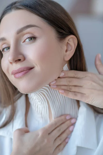 Linda mujer joven poniendo cintas en su cuello y buscando satisfecho — Foto de Stock