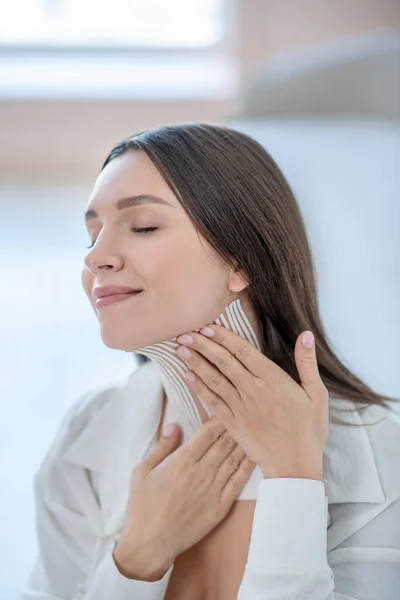 Mujer joven en blanco aplicando cintas en el cuello — Foto de Stock