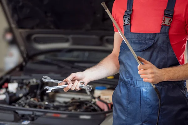 Auto mechanic hands with wrenches and lamp — Stock Photo, Image