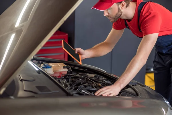 Man with tablet under hood of car — Stock Photo, Image