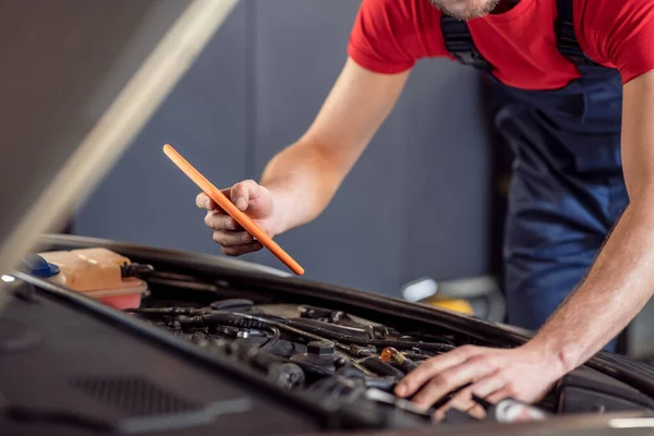 Manos masculinas con la tableta bajo el capó del coche — Foto de Stock