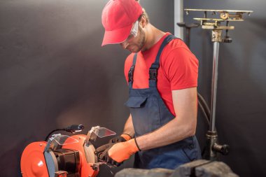 Man in overalls and goggles working near machine