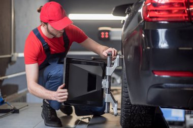 Man in work clothes straightening wheel of car