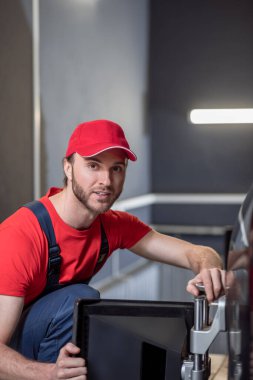 Experienced car service worker with wheel alignment stand