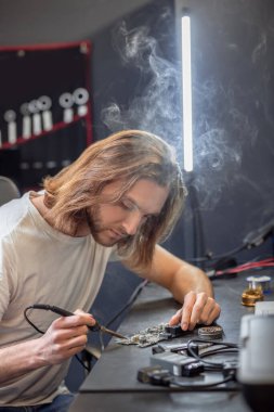 Interested man touching microcircuit with soldering iron