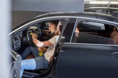 Man sitting in front seat of car cleaning