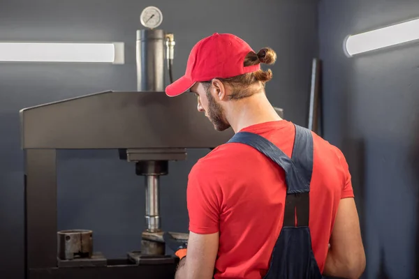 Man in overalls with detail near machine — Stock Photo, Image