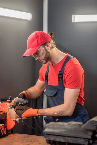Attentive man machining detail on grinding machine — Stockfoto