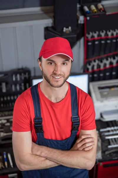 Joyful man in overalls and cap in workshop — Stock Photo, Image