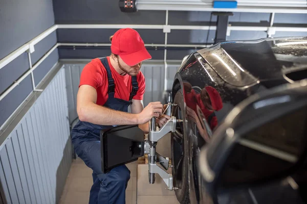 Auto mechanic in overalls near wheel of car — Stockfoto