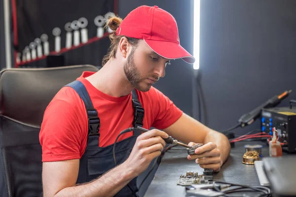 Man in overalls with soldering iron in workshop — Zdjęcie stockowe