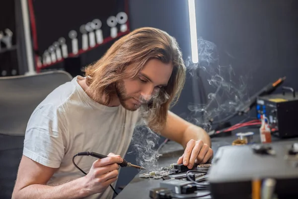 Hombre joven microcircuito de soldadura en taller — Foto de Stock