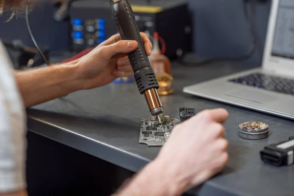 Male hands soldering microcircuit on table near laptop — Zdjęcie stockowe